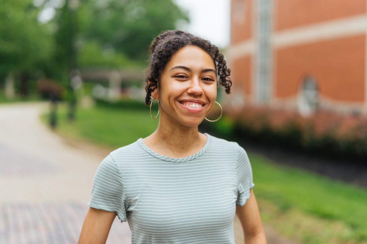 student outside Drinko Library smiling at the camera
