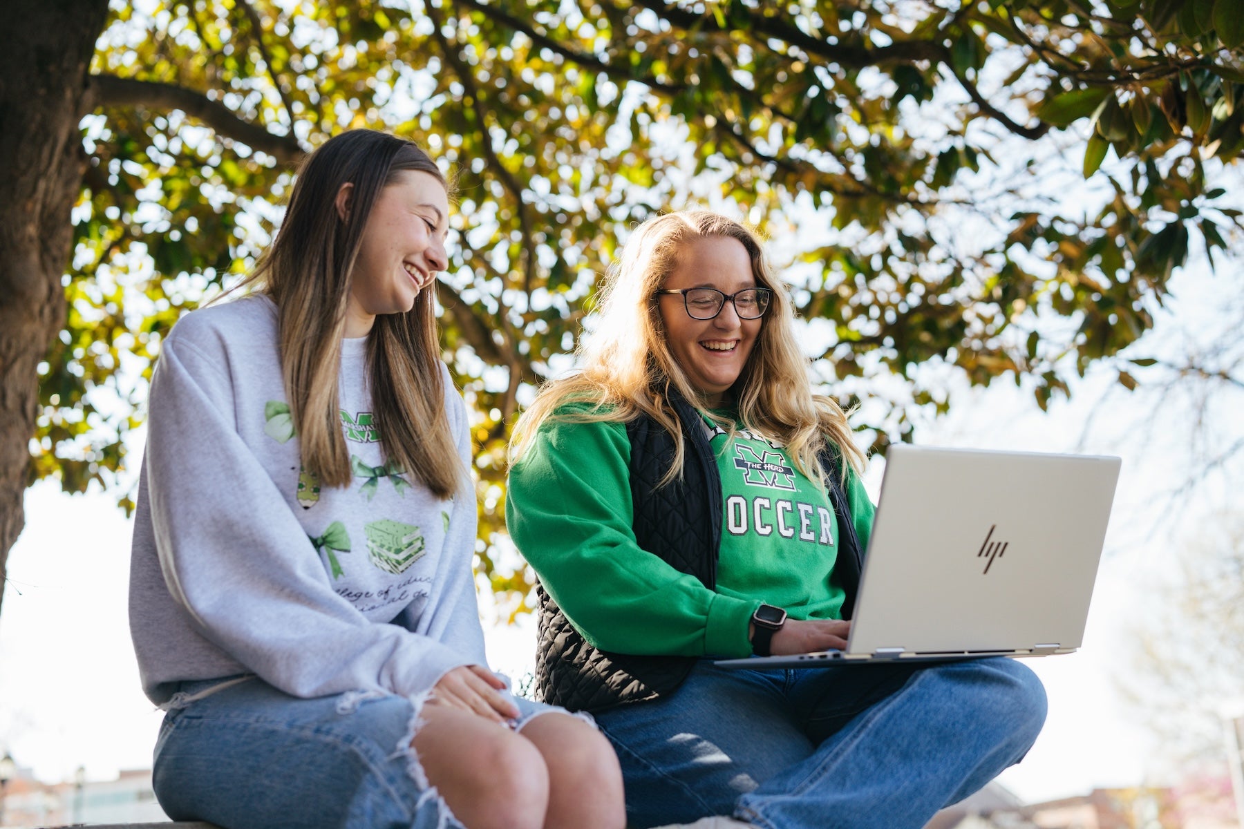 two students looking at a laptop outside
