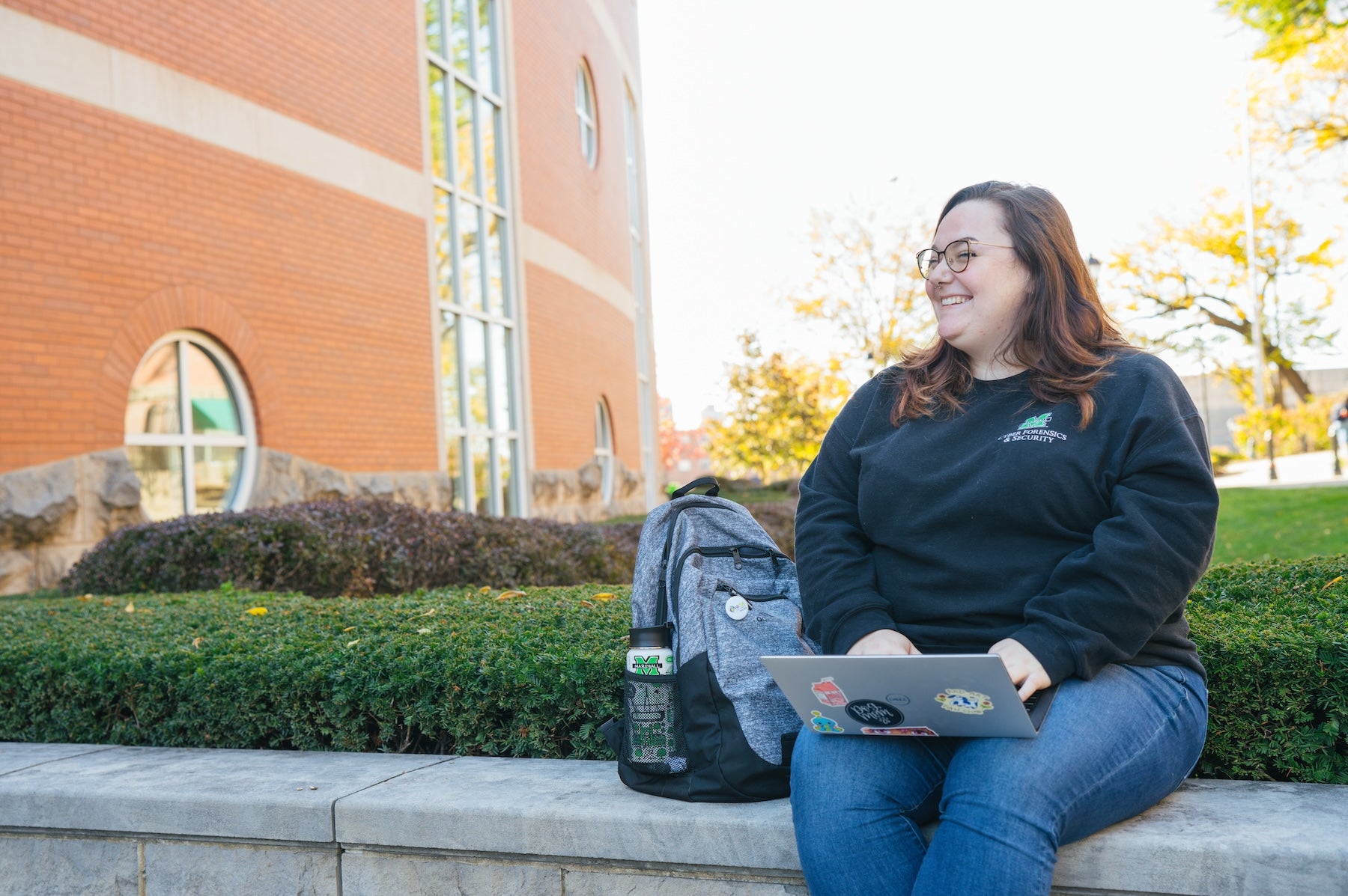 student working on a laptop outside Drinko Library