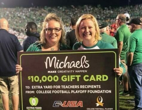 two people at a football game with a certificate for a $10,000 gift card