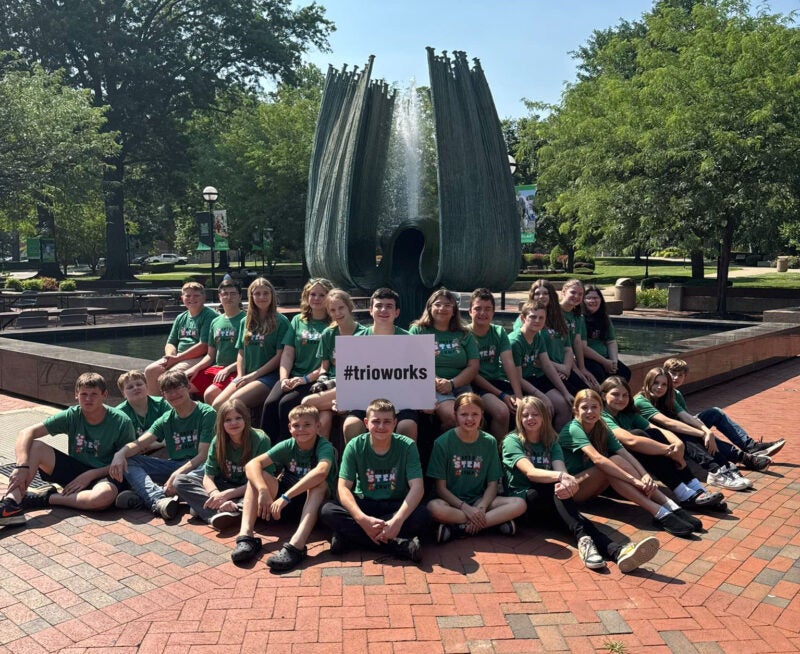 group of middle school students by the Memorial Fountain with a sign that reads