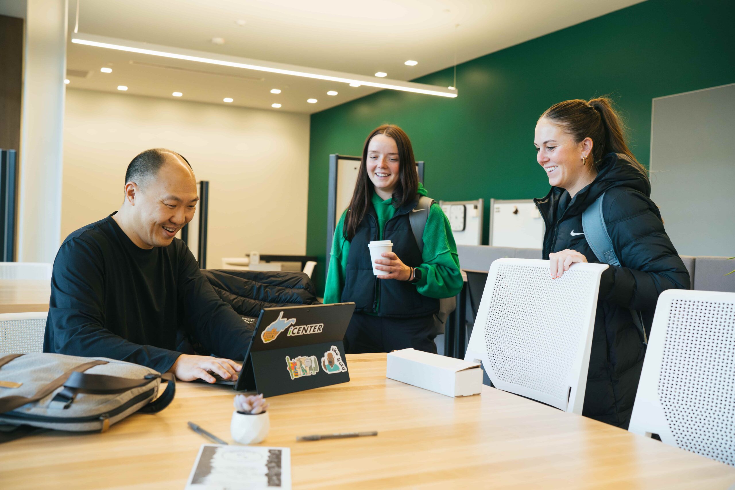 two students working with Ben Eng in the business school