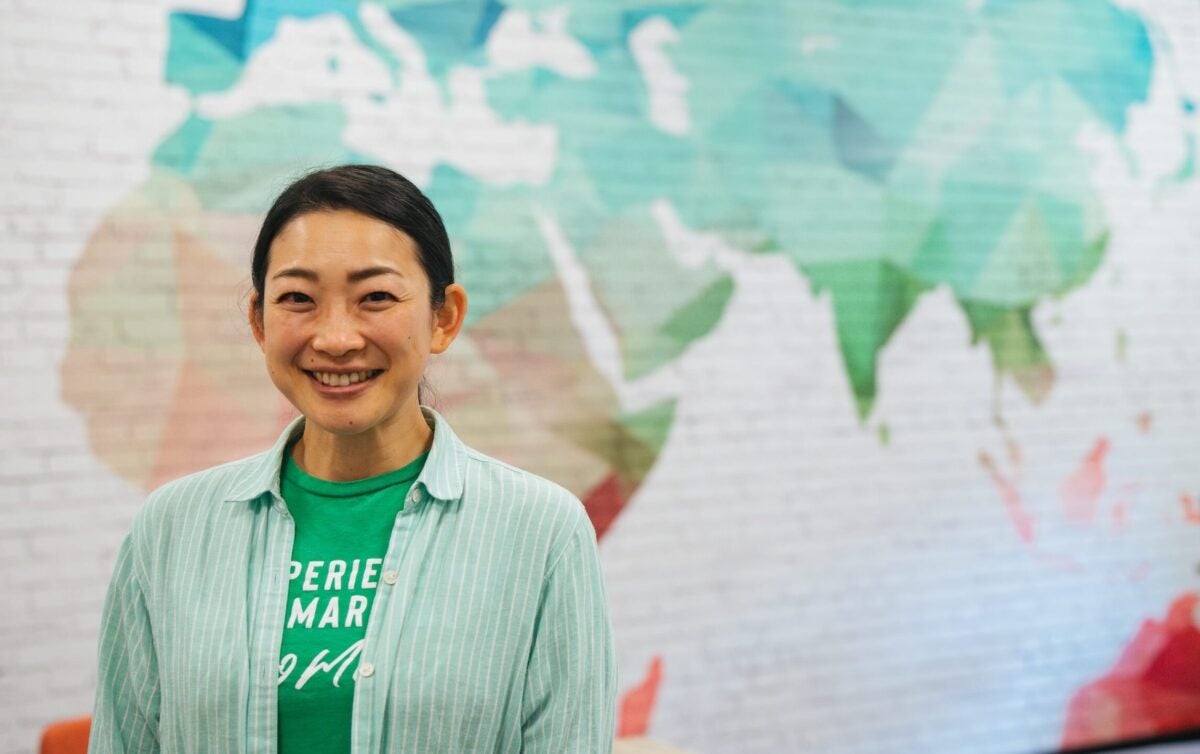 student smiling in front of a map on campus