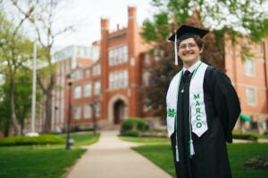 Luke Jeffrey wears his graduation cap, gown and Marco stole outside of Marshall University's Old Main.