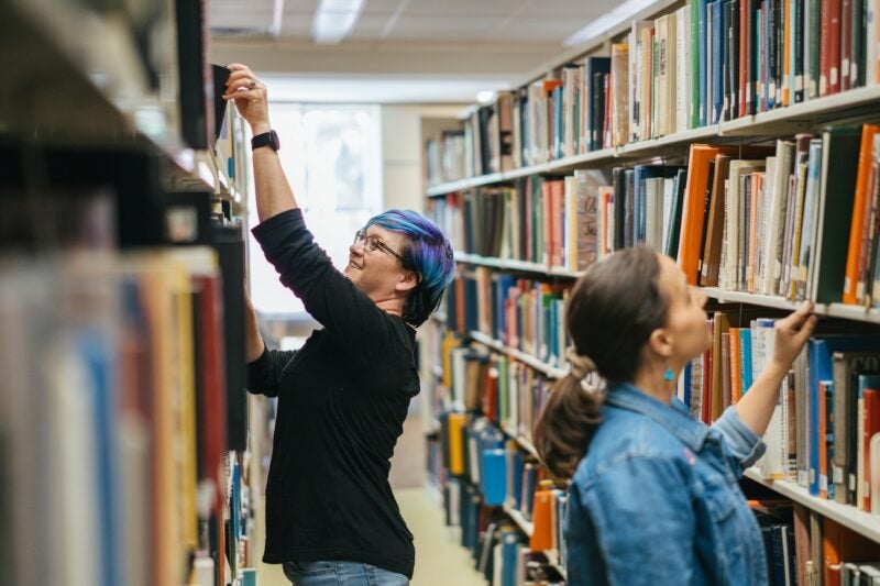 two people looking at bookshelves in the library