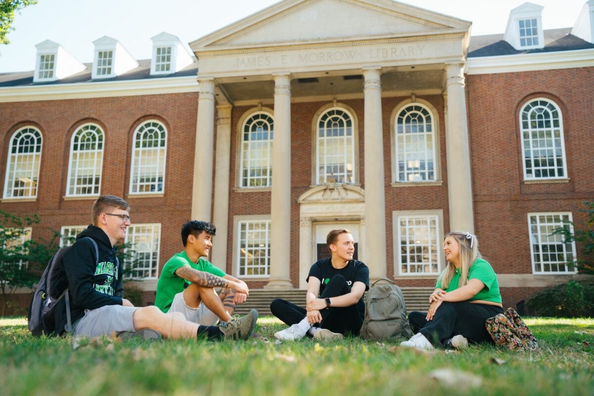 students sitting on the lawn on Morrow Library talking