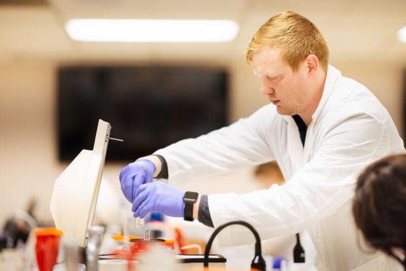 student working in a lab in a lab coat on microscope slides