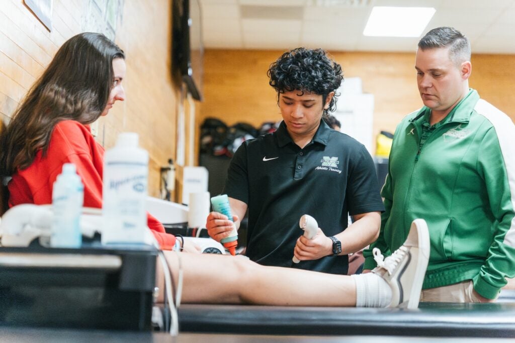 athletic training photo of someone doing an ultrasound on a knee with a professor supervising